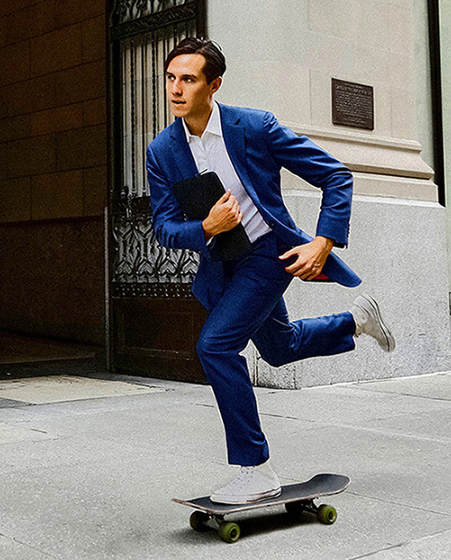 Business man in a suit skateboarding in the street