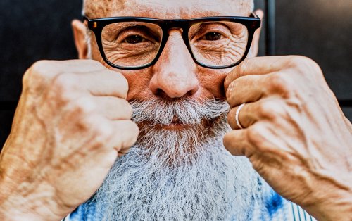 Older man with moustache and beard, touching his moustache