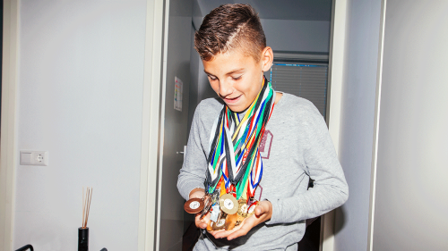 Young boy proudly showing medals