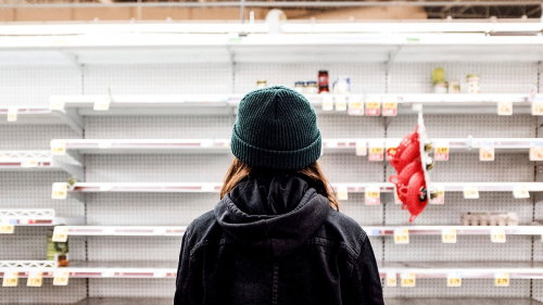 long haired person looking at an empty shelf in a supermarket