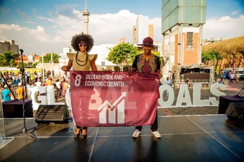 Singing duo Mafikizolo raised a flag to represent Goal 8, Decent Work and Economic Growth, at Constitution Hill in Johannesburg, South Africa, to support the UN Global Goals for Sustainable Development. Credit: Nicki Priem